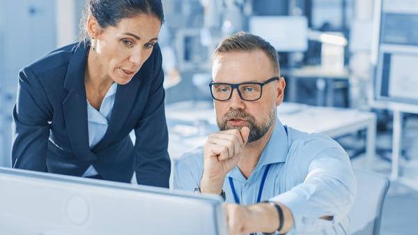 managers discussing regulatory compliance at computer desk